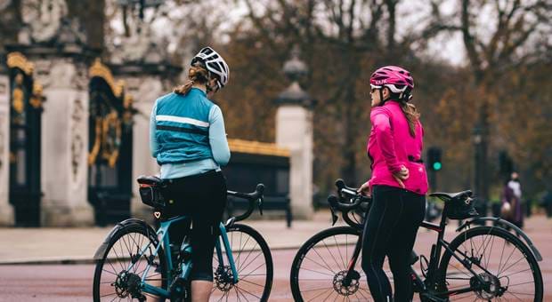 Two people sat on bikes outside of Buckingham Palace gates