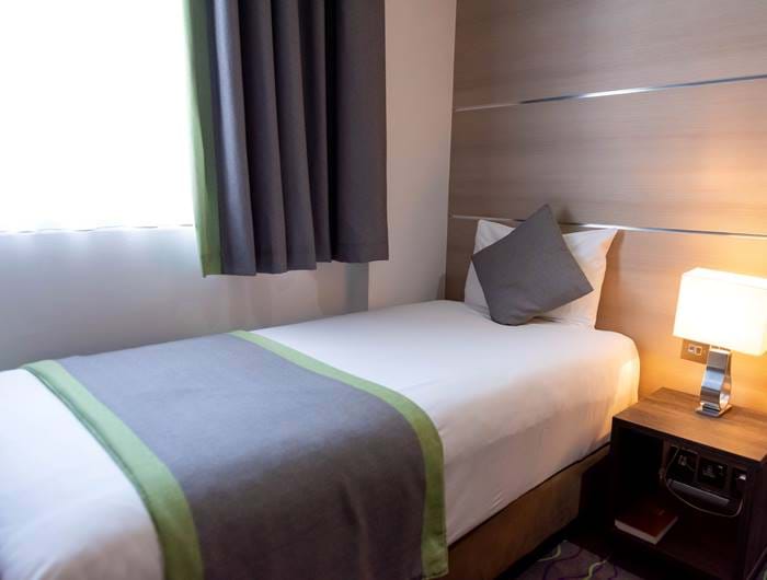 the bed of a single room at The Wesley London Euston Hotel