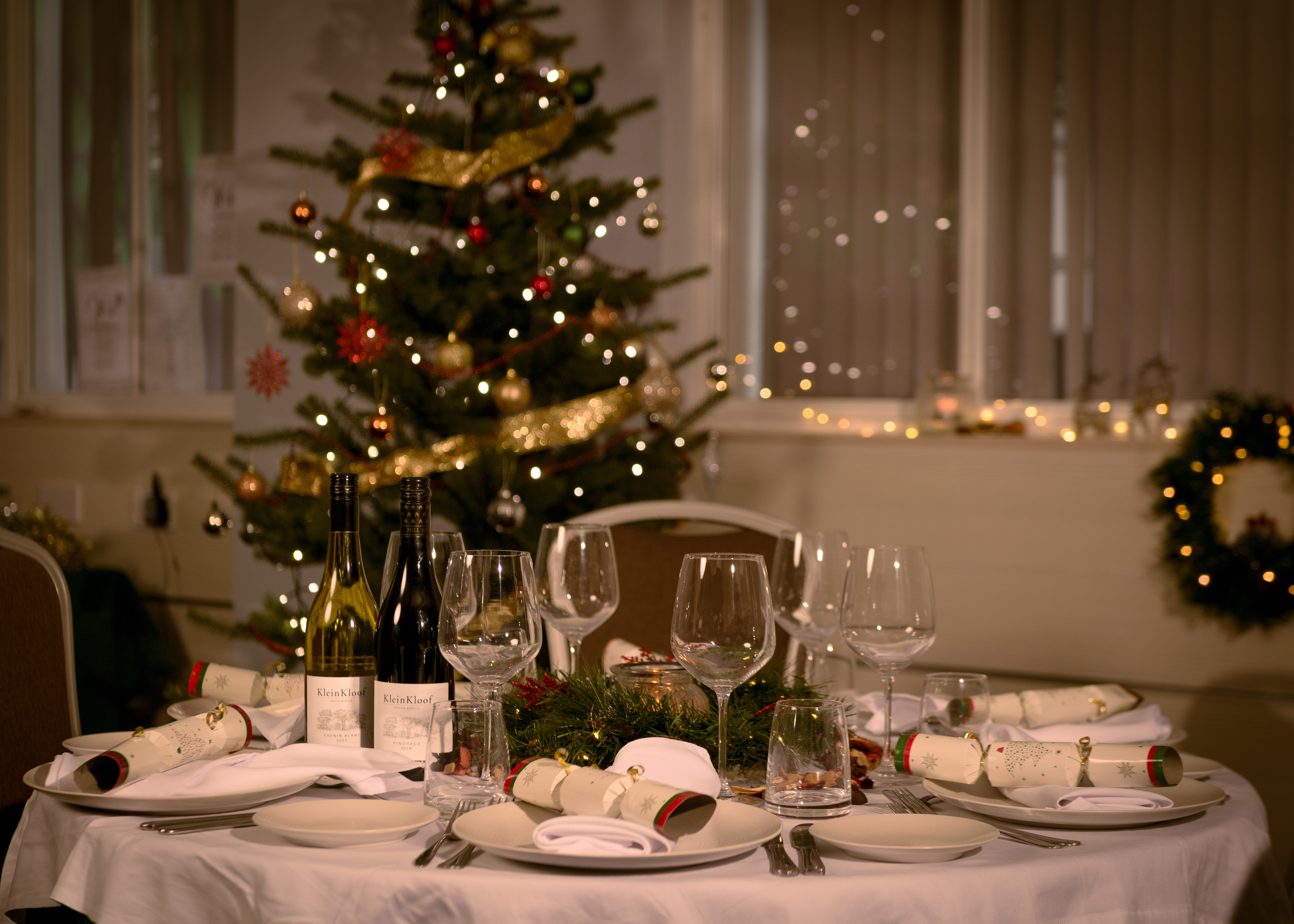 Table laid for Christmas lunch with a Christmas tree in the background