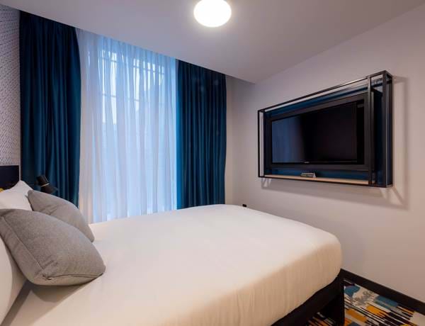 the bed and wall-mounted tv in the classic double bedroom of The Wesley Camden Town