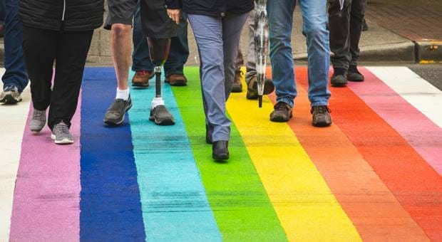 People walking over a rainbow flag
