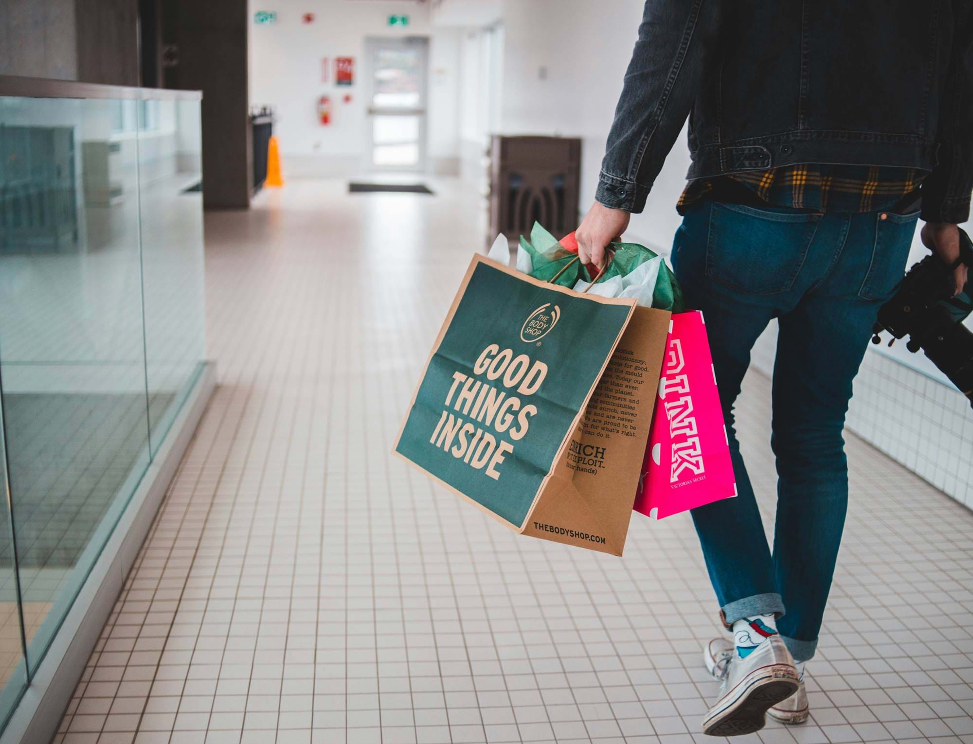 A man walking with a camera and shopping bags in his hands