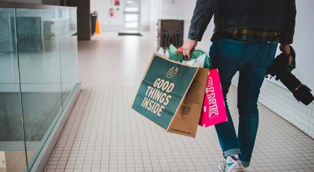 A man walking with a camera and shopping bags in his hands