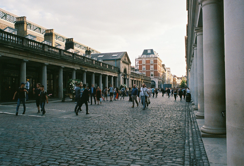 Covent Garden's main shopping strip in London with bystanders and cobbled floors